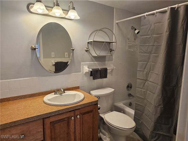 Full bathroom featuring vanity, tile walls, shower / bath combination with curtain, and toilet | Image 28