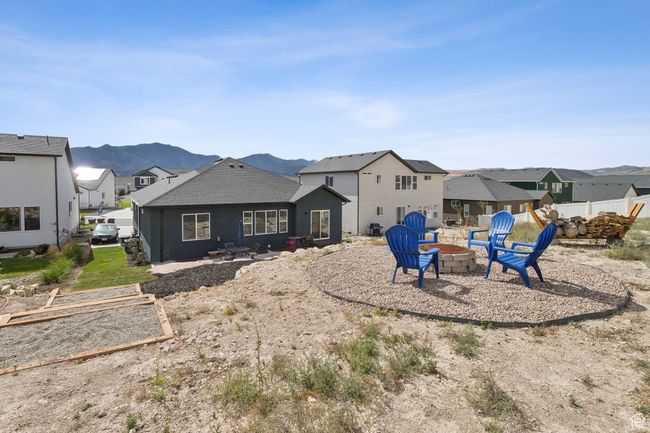 Back of property with a fire pit, a residential view, a mountain view, and roof with shingles | Image 8