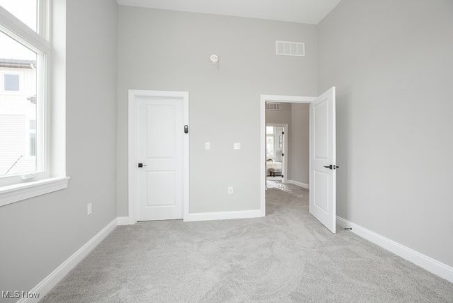 Unfurnished bedroom featuring light carpet, a towering ceiling, and multiple windows | Image 21