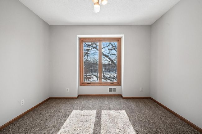 This bedroom features an oversized window that looks out to the lake and wooded backyard. | Image 25