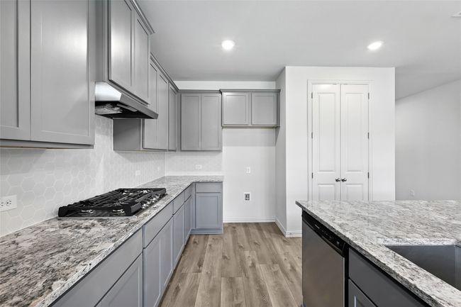 Kitchen with appliances with stainless steel finishes, gray cabinetry, under cabinet range hood, light wood-style flooring, and recessed lighting | Image 6