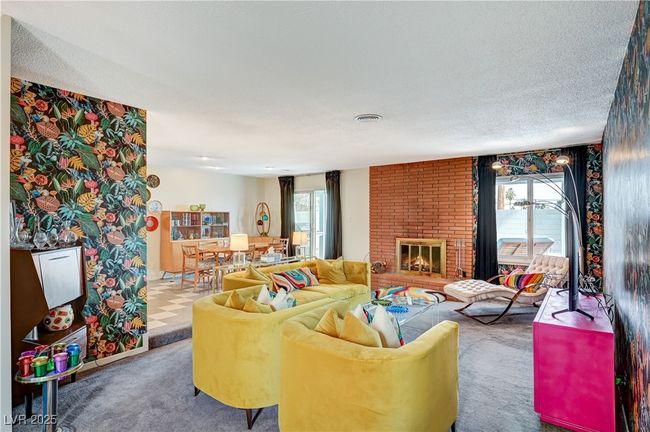 Carpeted living room with visible vents, a textured ceiling, a brick fireplace, and a wealth of natural light | Image 5