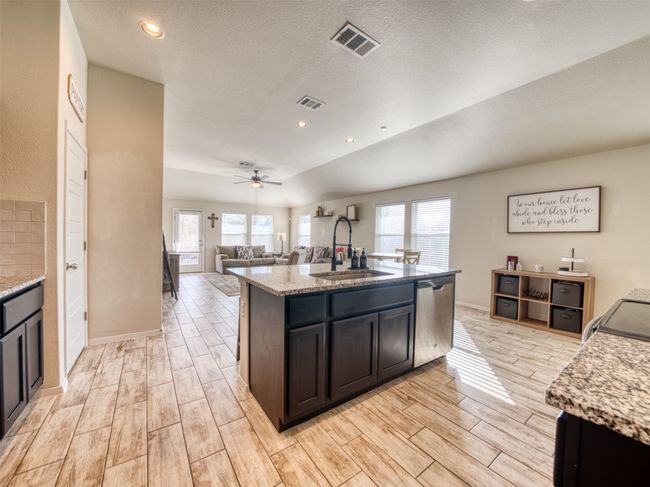 Kitchen with stainless steel dishwasher, ceiling fan, sink, light stone countertops, and a center island with sink | Image 8