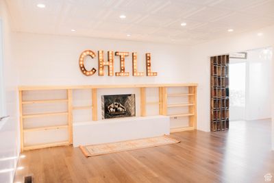 Living room featuring hardwood floors, storage shelves and a backlit CHILL sign | Image 2