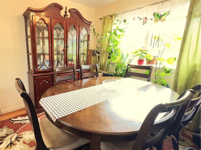 Dining area with laminate wood finished floors and natural light beaming through. | Image 5