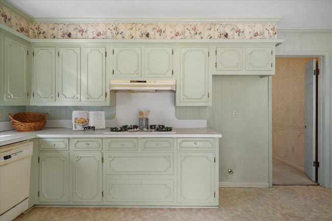Kitchen with under cabinet range hood, white appliances, green cabinetry, light countertops, and light floors | Image 13