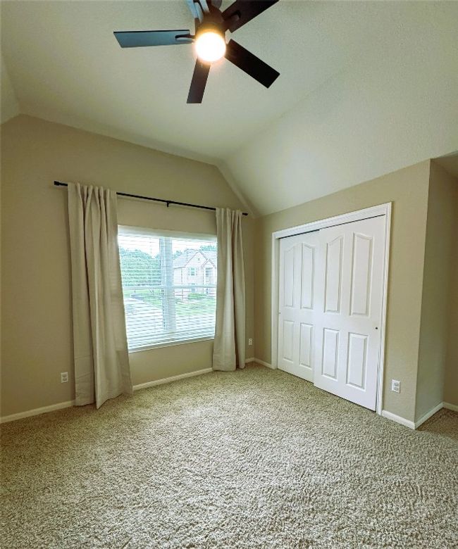 Upstairs Guest Bedroom #1 with vaulted ceiling, carpet, ceiling fan, and a closet. | Image 19