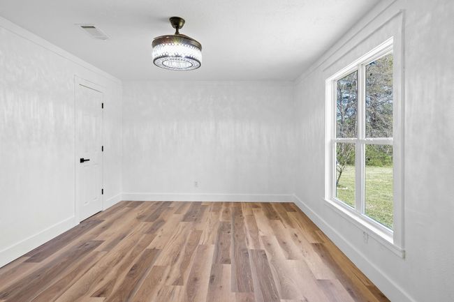 Spare room with a notable chandelier, visible vents, baseboards, and wood finished floors | Image 28