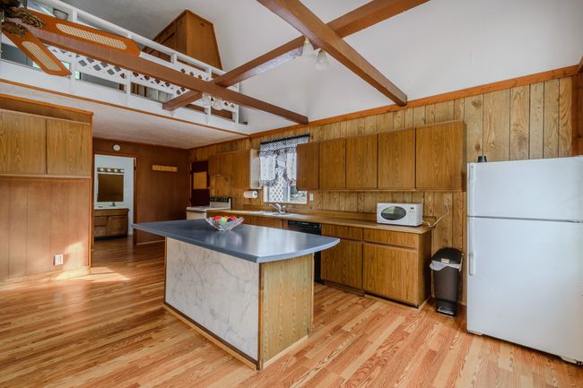 Kitchen featuring lofted ceiling with beams, white appliances, light hardwood / wood-style floors, and a center island | Image 30