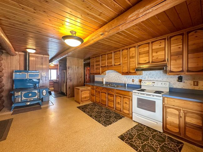 Kitchen with beamed ceiling, white electric stove, sink, and wooden ceiling | Image 25