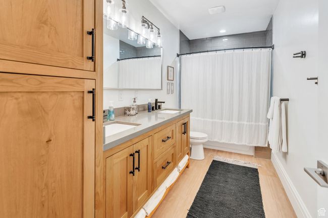 Full bathroom featuring wood finished floors, double vanity, and shower / bath combination with curtain | Image 55