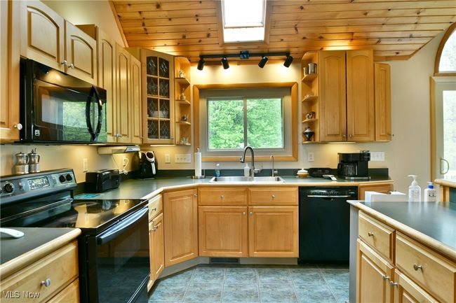 Kitchen featuring black appliances, a sink, open shelves, wood ceiling, and glass insert cabinets | Image 14