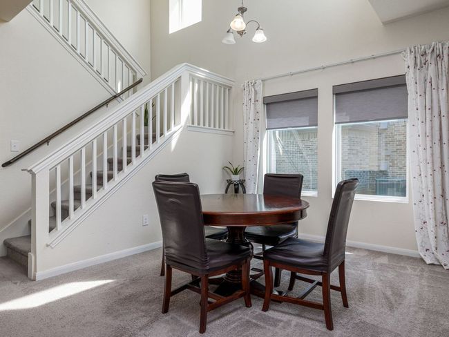 Carpeted dining space with stairway, a high ceiling, a chandelier, and baseboards and soaring ceiling | Image 7