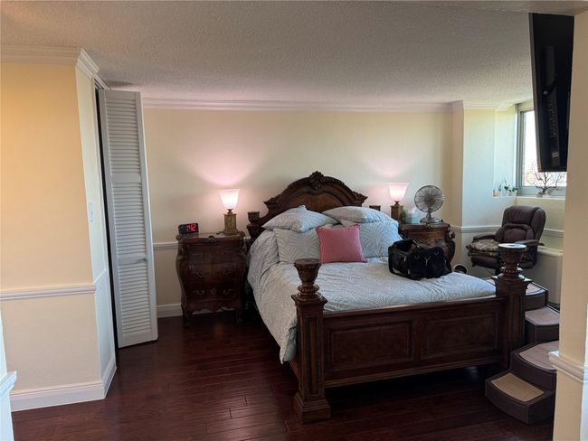 Bedroom with dark wood-style floors, ornamental molding, and a textured ceiling | Image 8