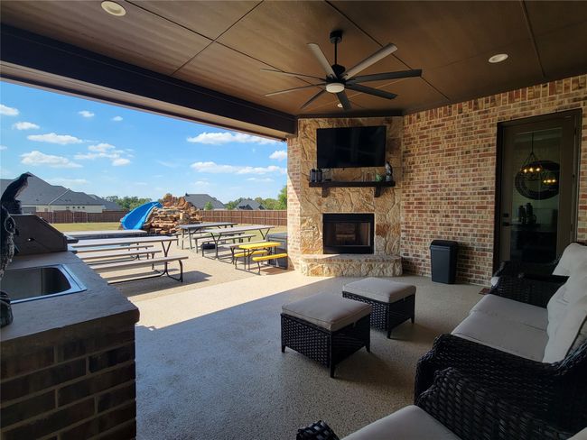 View of patio with ceiling fan and an outdoor living space with a fireplace | Image 8