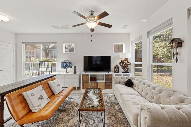 Living area with ceiling fan, visible vents, and a wealth of natural light | Image 6