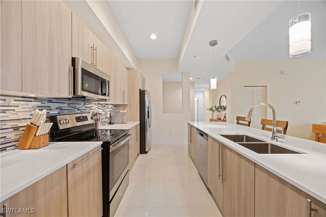 Kitchen with modern cabinets, appliances with stainless steel finishes, a sink, light brown cabinets, and backsplash | Image 13