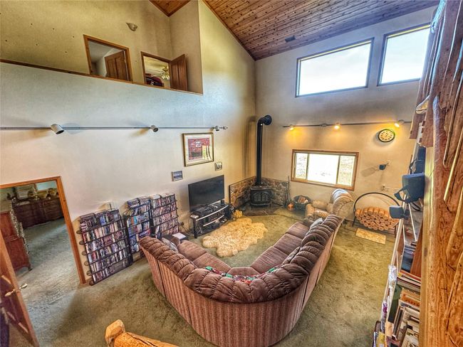 Living room featuring high vaulted ceiling, a wood stove, wood ceiling, and carpet floors | Image 20
