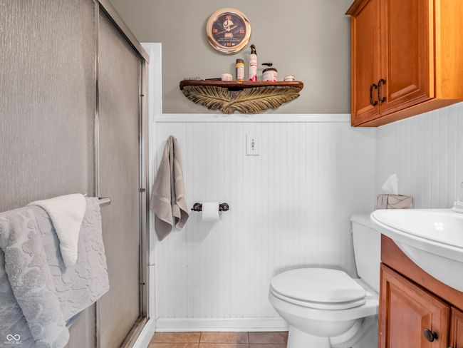 bathroom featuring vanity, a wainscoted wall, tile patterned flooring, and a stall shower | Image 28