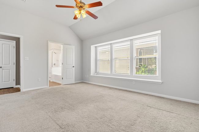Primary bedroom with vaulted ceiling, carpet flooring, ceiling fan, and ensuite bath | Image 18