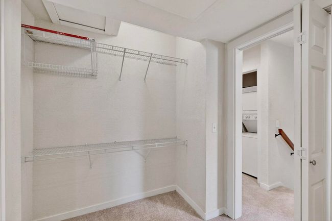 Spacious closet with light colored carpet and stacked washer / dryer | Image 33
