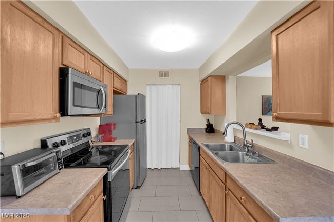 Kitchen featuring a sink, light tile patterned floors, visible vents, a toaster, and appliances with stainless steel finishes | Image 8