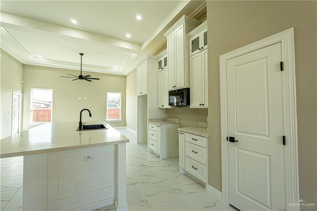Kitchen with ceiling fan, marble finish floor, black microwave, a sink, and recessed lighting | Image 20