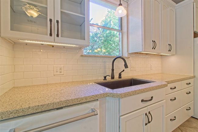 Kitchen with dishwasher, glass insert cabinets, white cabinetry, decorative backsplash, and light stone counters | Image 16