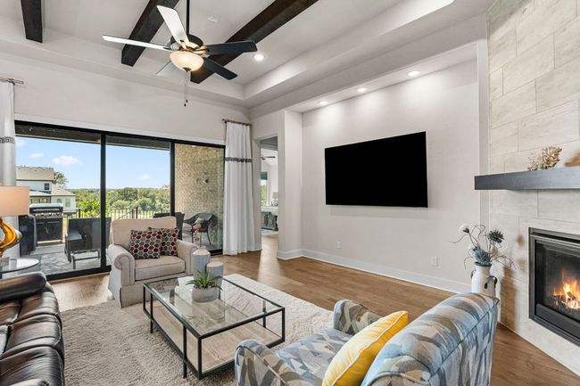 Living room featuring a ceiling fan, baseboards, dark wood-style flooring, and a tile fireplace | Image 9