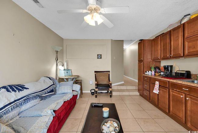 Living area with light tile patterned floors, visible vents, a textured ceiling, and ceiling fan | Image 26