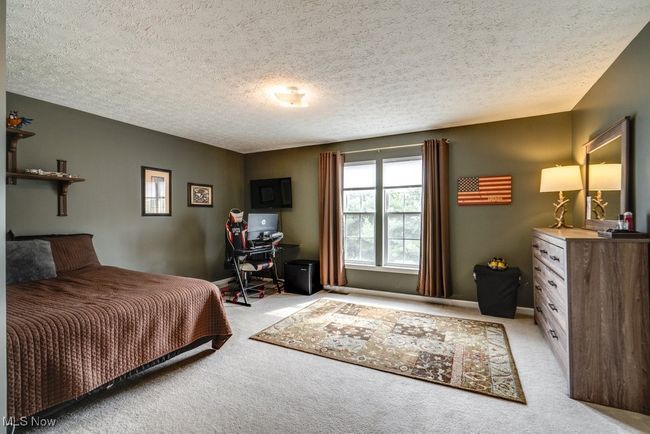 Bedroom with light colored carpet and a textured ceiling | Image 26