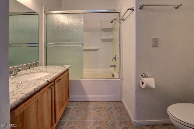 Bathroom with toilet, vanity, baseboards, and bath / shower combo with glass door | Image 14