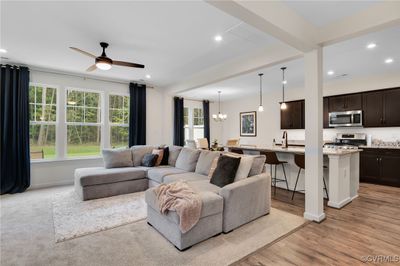 Living room with ceiling fan with notable chandelier and light wood-type flooring | Image 3