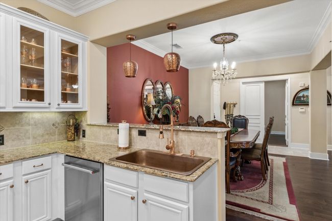 Kitchen with a sink, a peninsula, white cabinets, tasteful backsplash, and ornamental molding | Image 7