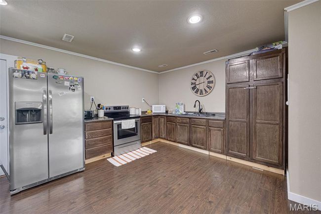 Kitchen with stainless steel appliances, a sink, ornamental molding, dark wood-type flooring, and recessed lighting | Image 6