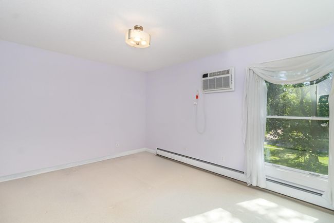 The primary bedroom has a beautiful outdoor view and includes a second wall-unit air conditioner. | Image 9