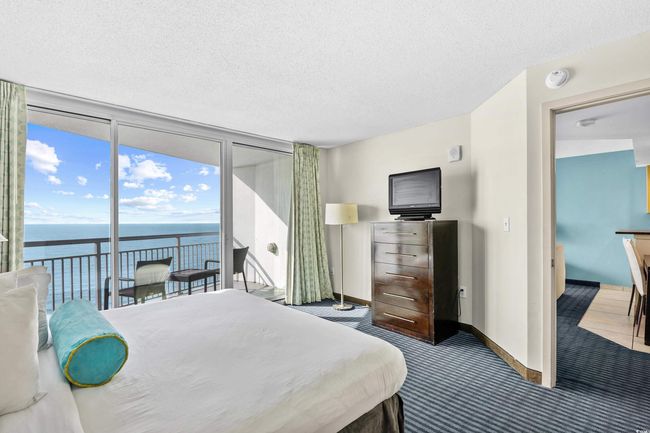 Bedroom with carpet, a water view, access to exterior, expansive windows, and a textured ceiling | Image 21