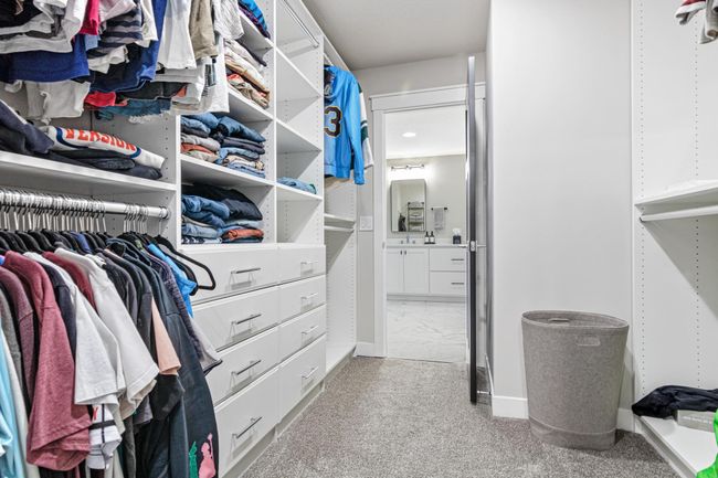Primary walk in closet connecting the bathroom and laundry room | Image 37