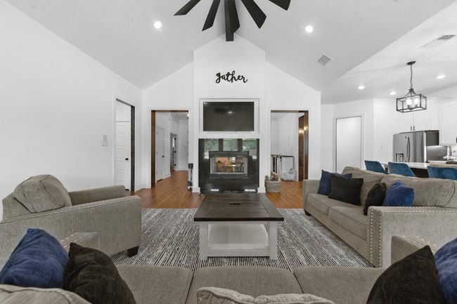 Living area with high vaulted ceiling, visible vents, wood finished floors, and ceiling fan | Image 12