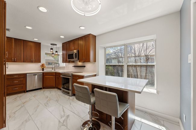 Kitchen featuring light countertops, a sink, appliances with stainless steel finishes, brown cabinets, and recessed lighting | Image 12