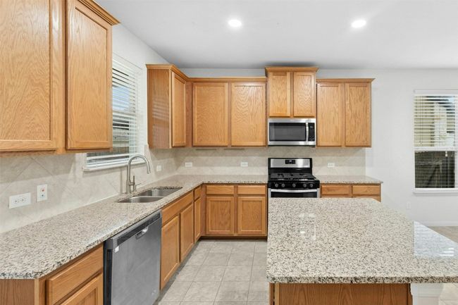 The kitchen features granite countertops, stainless steel appliances, a center island, and tons of storage and prep space. | Image 5