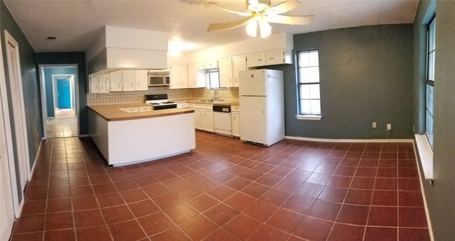 Kitchen with white appliances, a sink, dark tile patterned flooring, tasteful backsplash, and ceiling fan | Image 15
