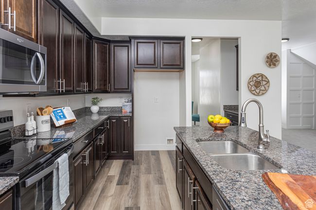 Kitchen featuring electric range, stainless steel microwave, dark stone counters, and a sink | Image 7