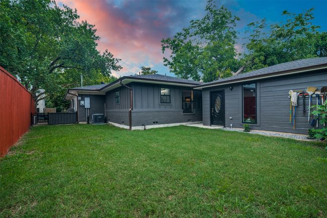 Back of house at dusk featuring board and batten siding, brick siding, roof with shingles, and crawl space | Image 40