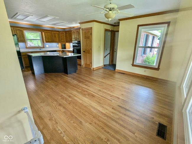 kitchen with freestanding refrigerator, brown cabinetry, a center island, light wood finished floors, and light countertops | Image 49