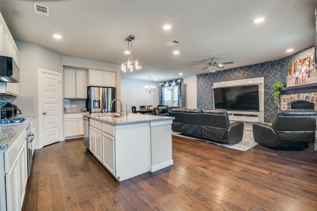 Kitchen featuring open floor plan, appliances with stainless steel finishes, a chandelier, a ceiling fan, and light stone counters | Image 10