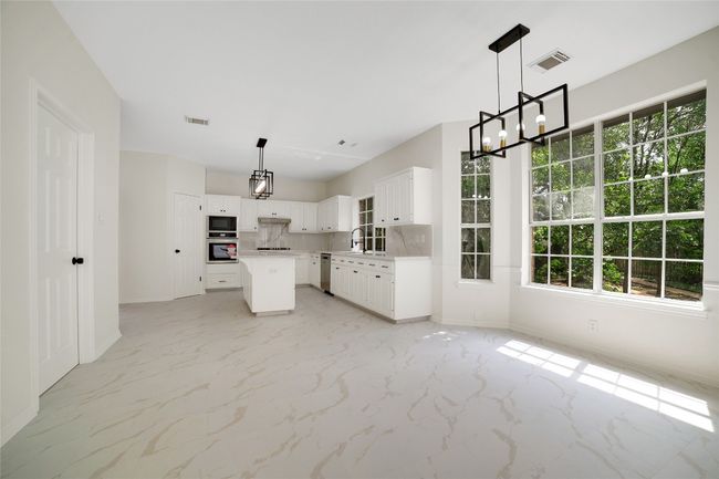 Kitchen with stainless steel appliances, light marble finish floors, a chandelier, and a center island | Image 4