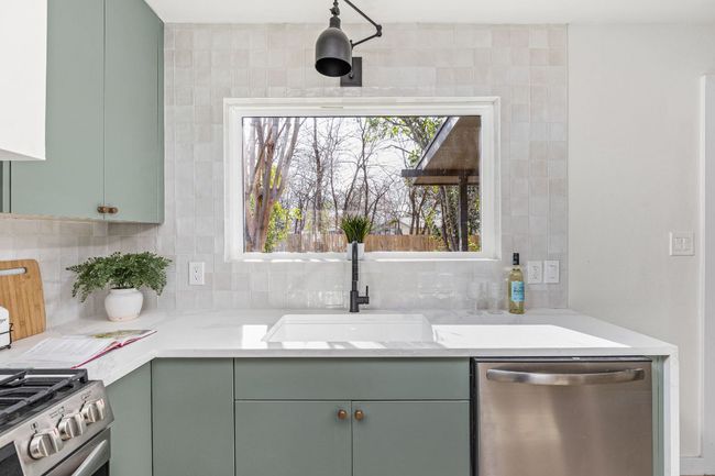Kitchen with appliances with stainless steel finishes, green cabinets, tasteful backsplash, and light stone countertops | Image 17