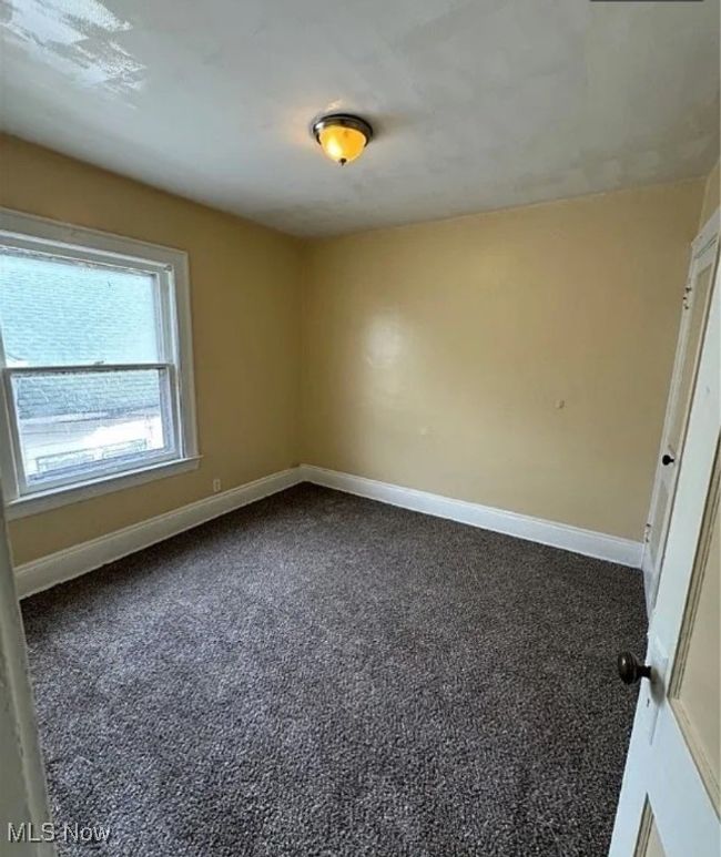 Unfurnished room featuring dark colored carpet and baseboards | Image 4