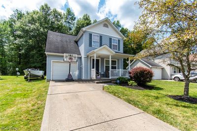 View of front property featuring a garage, a front yard, and covered porch | Image 1